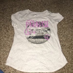 Greyish-white t-shirt with paradise written in pink sparkly letters